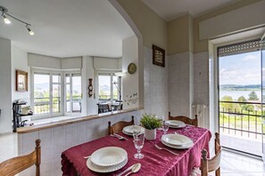 Een eetgedeelte met een tafel voor vier personen, een plant in pot en uitzicht op de omgeving.