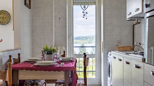 Une cuisine avec un coin repas, un lave-linge et une vue sur l’extérieur, visible à travers une porte.