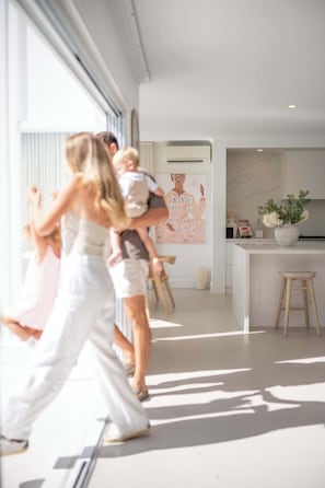 Una cocina moderna con encimera de mármol, un jarrón blanco con flores y un taburete de madera.
