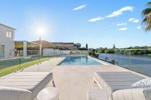 A swimming pool with a glass barrier, outdoor seating, and a view of a river. - Whitesands by Aryve | Robina (Robina)