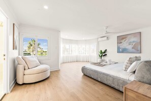 A modern living room with a sofa, a chair, a bed, and a large window with curtains. - Whitesands by Aryve | Robina (Robina)