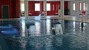 En inomhuspool med vattenstrålar, röda väggar och några få stolar.