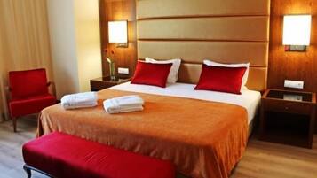 A hotel room with a large bed, two bedside tables, a chair, and a bench.