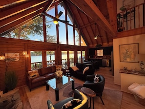 A spacious cabin interior with a dining area, kitchen, and large windows overlooking a lake. - Main Channel Point Lot Lakefront Retreat - Sweeping Views, Private Dock + Lift (Lake Norman of Catawba)