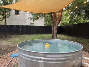 A metal water tank with a rubber duck, surrounded by a tree and a black fence. - 2BR Cowboy Pool Home ❤️ Walk to Barton Springs, Zilker near Eatery, Downtown (Austin)