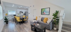 A modern living room with a sofa, coffee table, and dining area.
