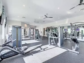 A modern gym with various exercise equipment, including a rowing machine and weight machines. - Modern Resort Condo Minutes to Disney (Kissimmee)