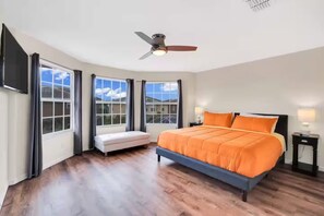 Ein Schlafzimmer mit Bett, Deckenventilator, Fensterbank und Blick ins Freie.