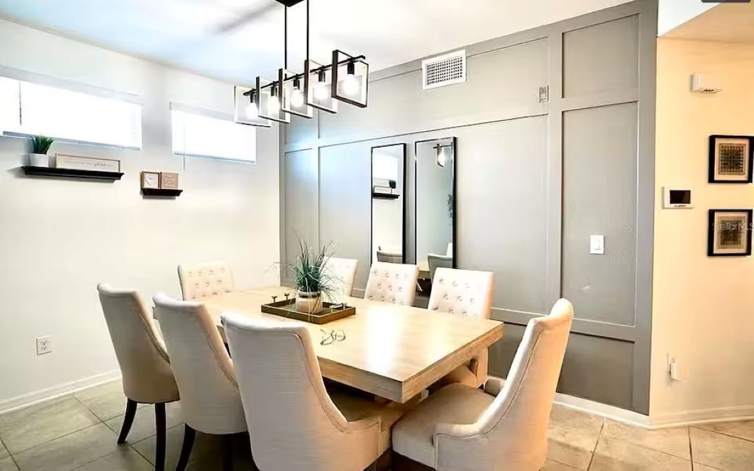 A dining area with a wooden table, six chairs, and a chandelier.