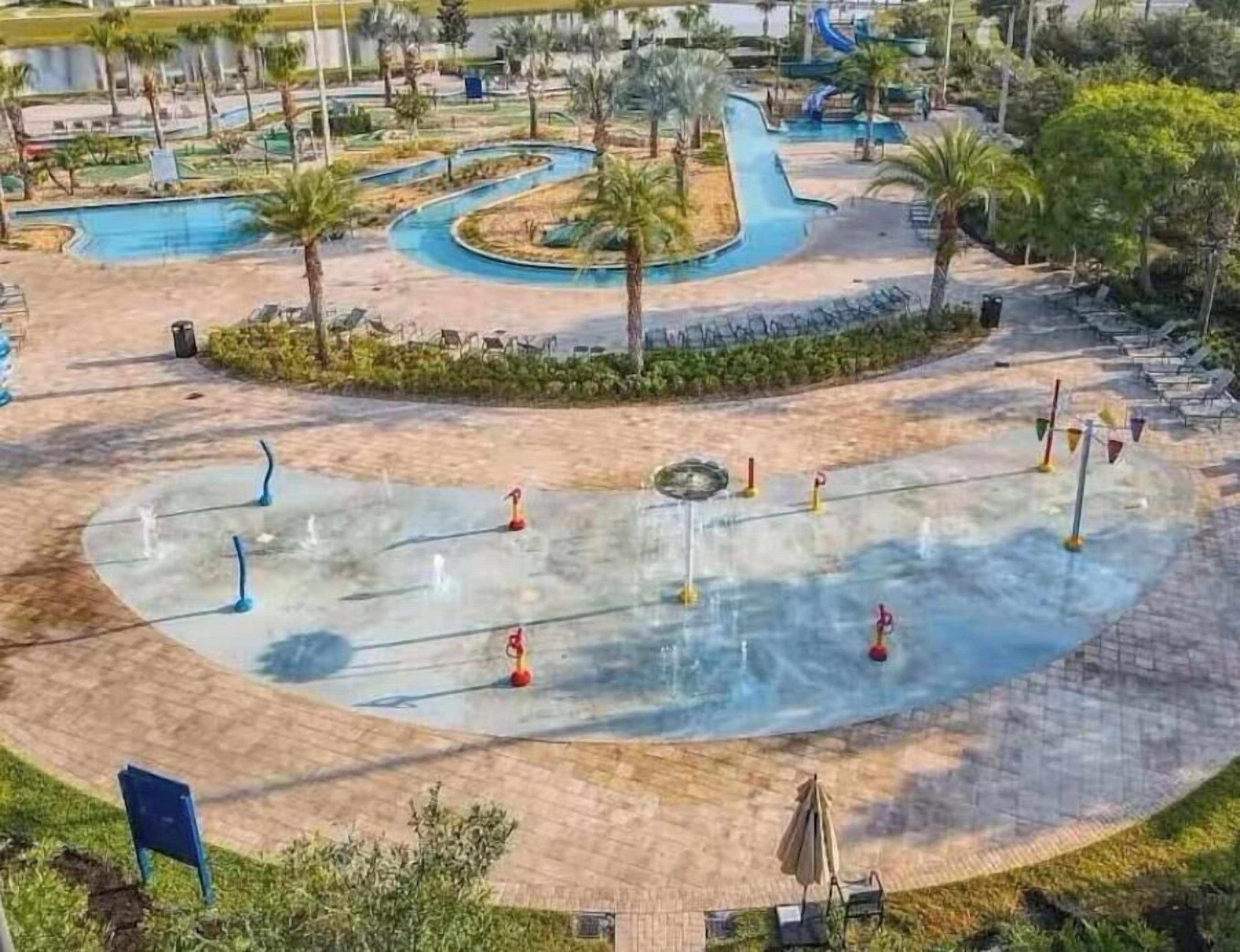 Un parc aquatique doté d’une piscine sinueuse, de palmiers et de chaises longues.