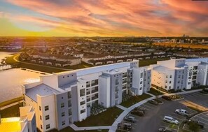A multi-story residential building with a parking lot and a river in the background. - Resort Getaway Near Disney (Kissimmee)