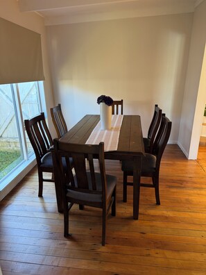 A dining area with a wooden table, six chairs, and a vase with flowers.