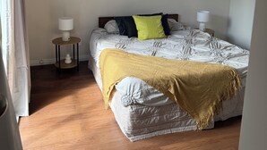 Ein Schlafzimmer mit einem Bett, Nachttischen, einem Fenster und einer Deckenleuchte.