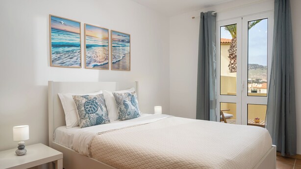 Une chambre à coucher avec un lit, une table de chevet et une vue sur l’extérieur.