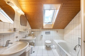 Ein modernes Badezimmer mit Oberlicht, einer Badewanne und einer Toilette.