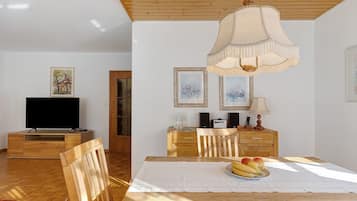 A dining area with a wooden table, chairs, a television, and artwork on the walls.