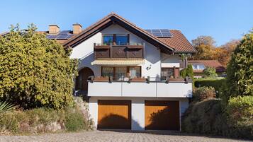 Ein zweistöckiges Haus mit Balkon, Solaranlage und Garage.