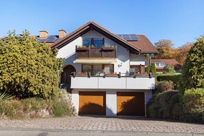 A two-story house with a balcony, solar panels, and a garage. - Beautiful Ground Floor Apartment with Dreiwelten Card and Terrace near Solemar (Bad Dürrheim)