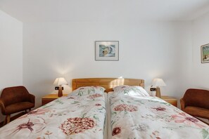 A bedroom with two single beds, wooden headboards, a nightstand with a lamp, and a chair. - Beautiful Ground Floor Apartment with Dreiwelten Card and Terrace near Solemar (Bad Dürrheim)