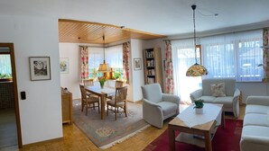 A living room with a dining area, a bookshelf, and a hanging light fixture. - Beautiful Ground Floor Apartment with Dreiwelten Card and Terrace near Solemar (Bad Dürrheim)