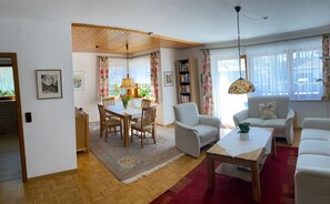 Ein Wohnzimmer mit Essbereich, einer Bücherwand und einer Pendelleuchte.