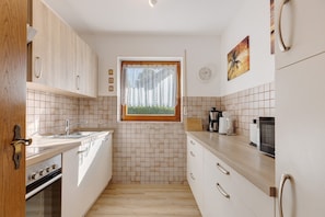 A kitchen with a window, tiled backsplash, wooden cabinets, and a stove. - Beautiful Ground Floor Apartment with Dreiwelten Card and Terrace near Solemar (Bad Dürrheim)