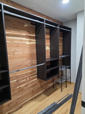 Una habitación con paneles de madera en la pared, estanterías metálicas y suelo de madera.