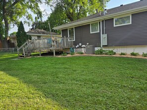 A residential house with a front yard, a wooden deck, and a large air conditioning unit. - Rest Easy in Rochester in this 3 bedroom home (Rochester)