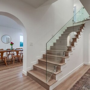 Ein modernes Interieur mit einer Treppe, Holzboden und einem Essbereich mit Stühlen und einem Tisch.