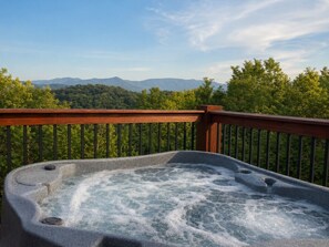 Uma banheira de hidromassagem em um deck com vista para montanhas e árvores.