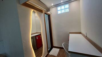 Una habitación pequeña con suelo de madera, un electrodoméstico rojo, un armario blanco y una ventana con vistas.
