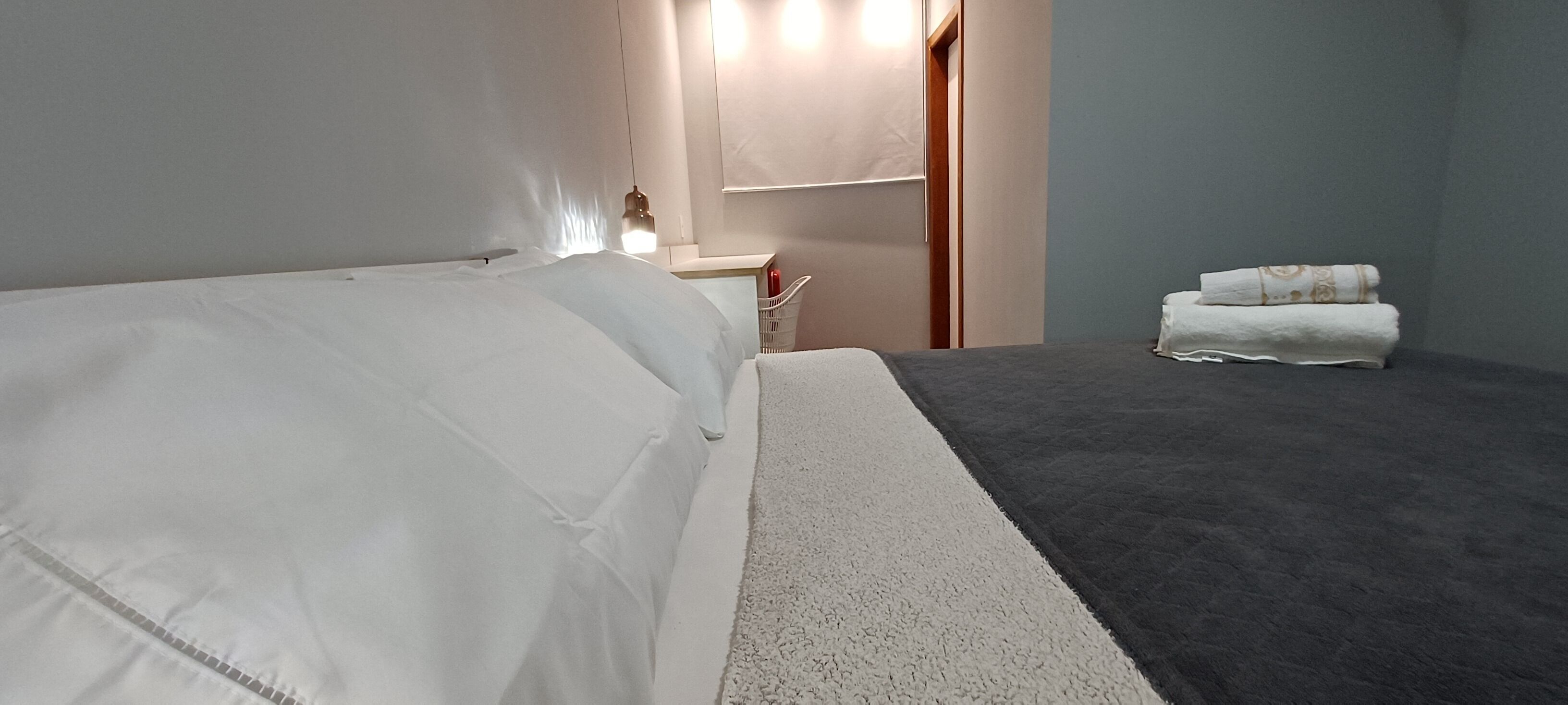 Ein Hotelzimmer mit Bett, Nachttisch, Spiegel und Handtuchhalter.