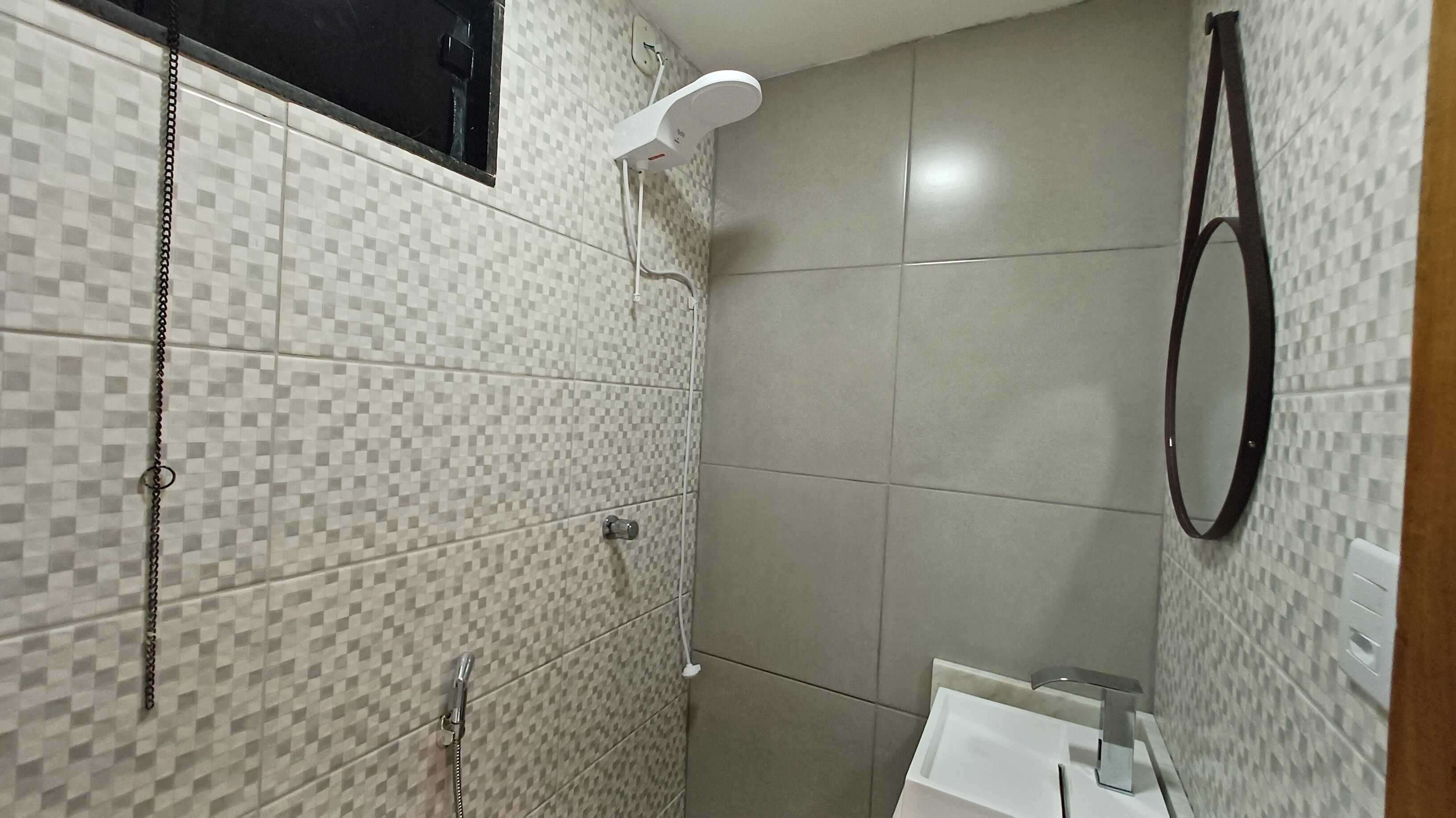 Un bany amb rajoles de vares, una dutxa, un mirall i un lavabo.