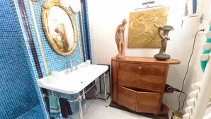 Een badkamer met een wit wastafel, een spiegel, een houten opbergmeubel en een sculptuur aan de muur.