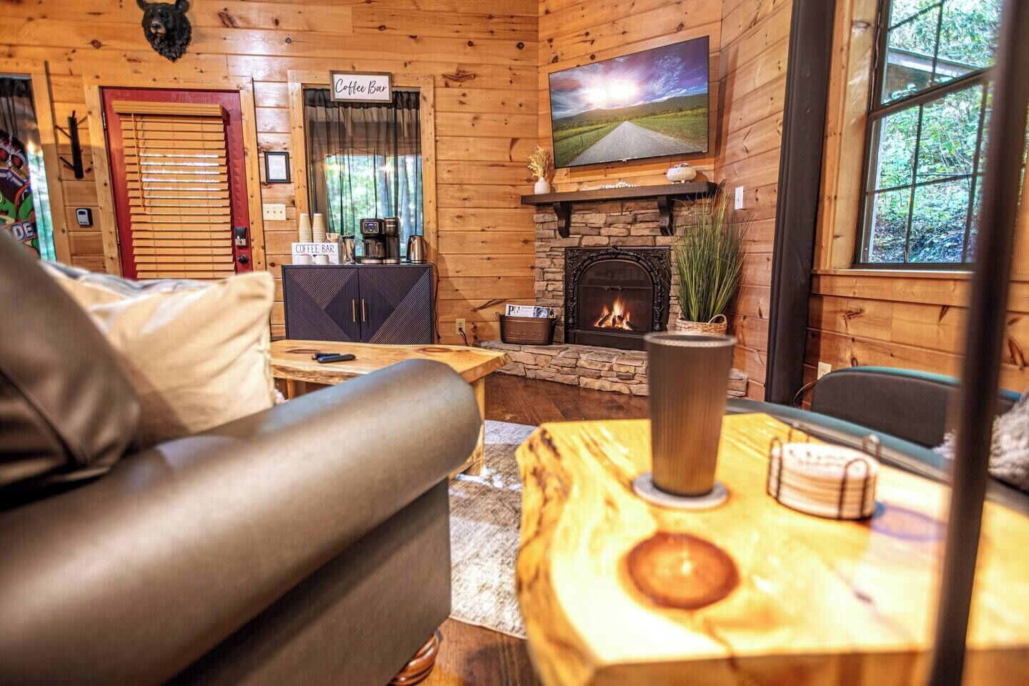 L’intérieur chaleureux d’un chalet avec une cheminée, un coin café et un téléviseur fixé au mur.