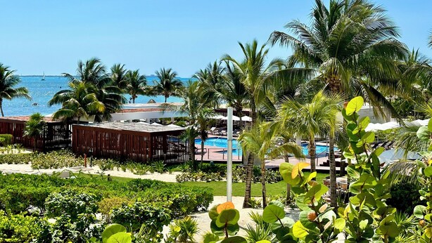 Een resort met een zwembad, palmbomen en uitzicht op de oceaan.