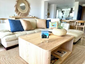 Una sala de estar moderna con una mesa de centro de madera, una revista y una planta decorativa.