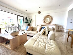 A modern living room with a sofa, coffee table, and a dining area with chairs.
