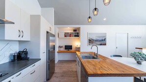 Eine moderne Küche mit weißen Schränken, einer Holzinsel, einem eingebauten Backofen und einem Edelstahl-Kühlschrank.