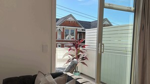 Ein Wohnzimmer mit einer Couch, einem Blumentopf und einer Glastür zum Balkon.