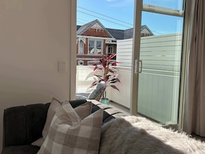 A living room with a sofa, a potted plant, and a sliding glass door leading to a balcony.