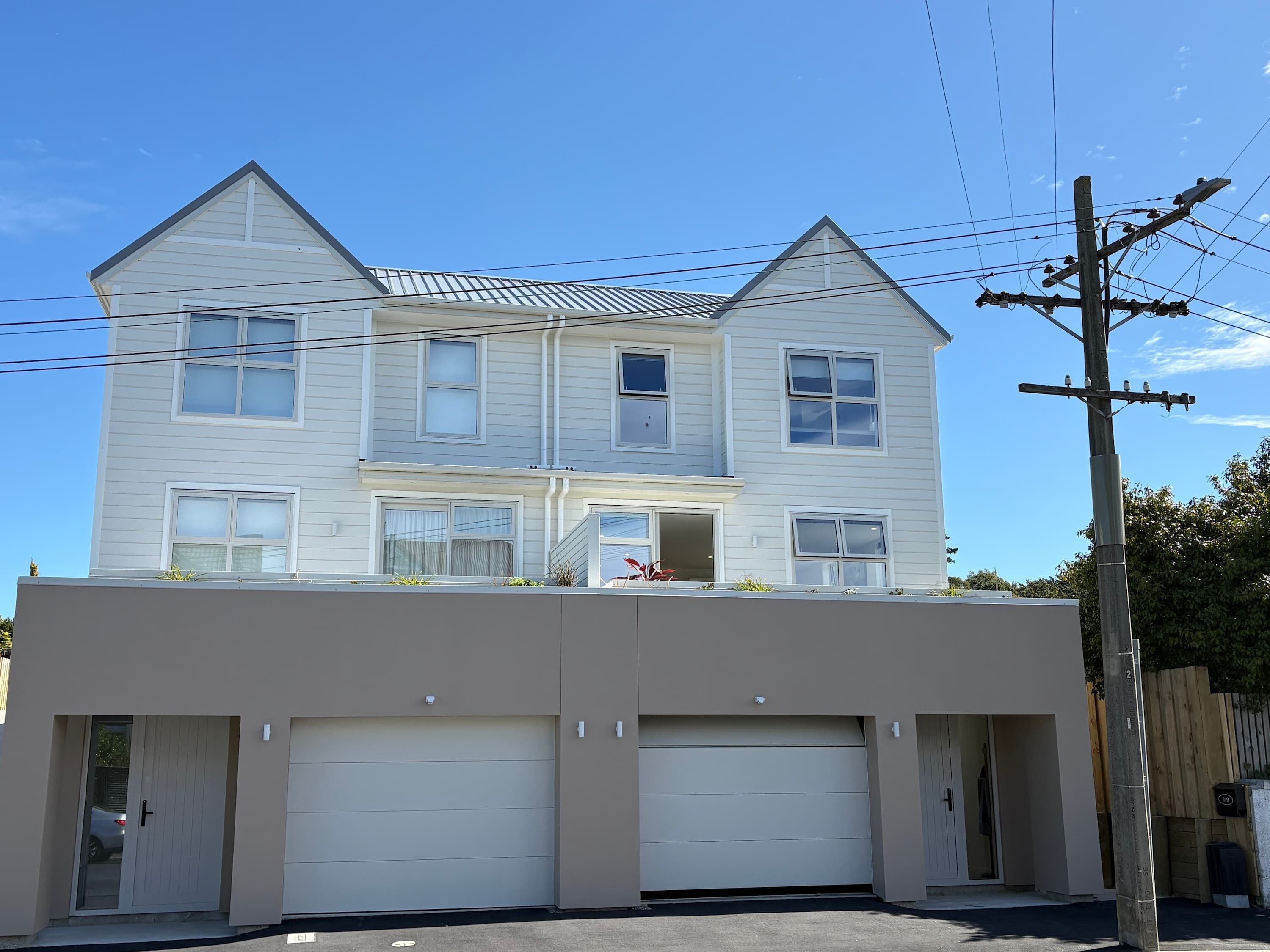 A two-story house with a garage, a balcony, and a wooden fence.