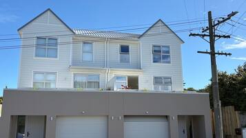 A two-story house with a garage, a balcony, and a wooden fence.