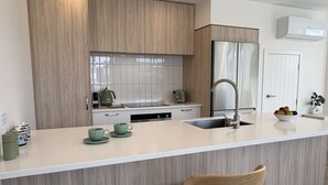 Eine moderne Küche mit Holzschränken, Edelstahlgeräten und einer weißen Arbeitsplatte.