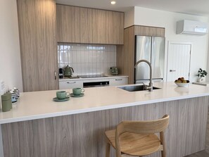 A modern kitchen with a wooden cabinet, stainless steel appliances, and a white countertop.