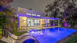 Ein modernes Haus mit Swimmingpool, überdachter Terrasse und gepflegtem Garten.
