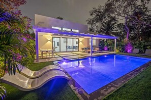 Ein modernes Haus mit Swimmingpool, überdachter Terrasse und gepflegtem Garten.