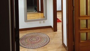 Un pasillo con suelo de madera, un espejo y una puerta.