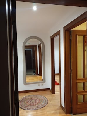 A hallway with a wooden floor, a mirror, and a door. - Oceanview First Line with 2 Pools 6 (Ovar)