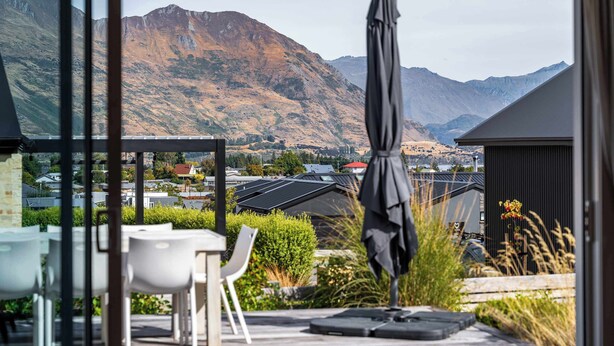 Een terras met zitplaatsen buiten en uitzicht op bergen.